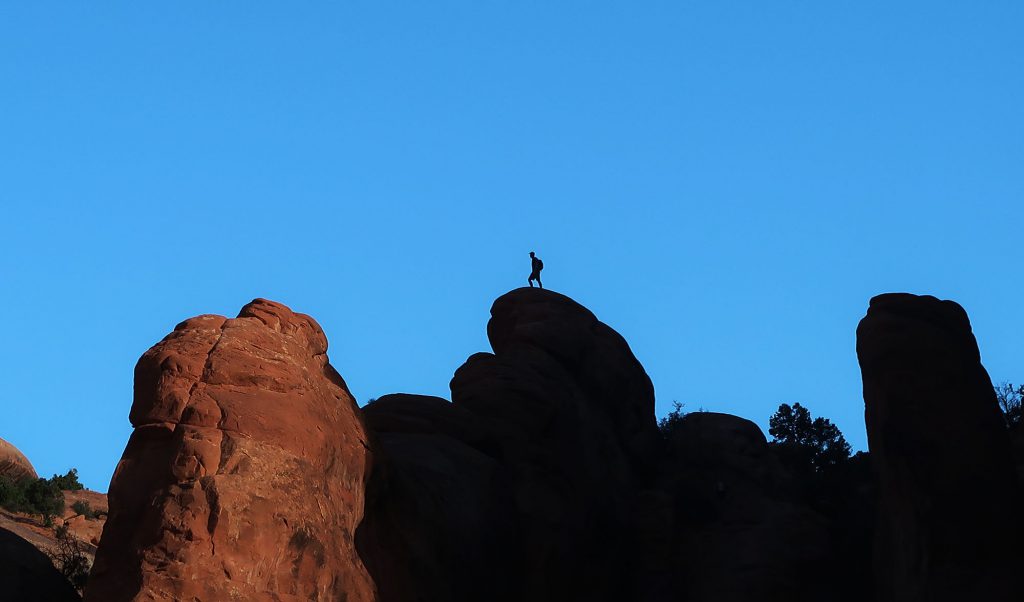 A lone hiker atop rock formations in Arches NP.
