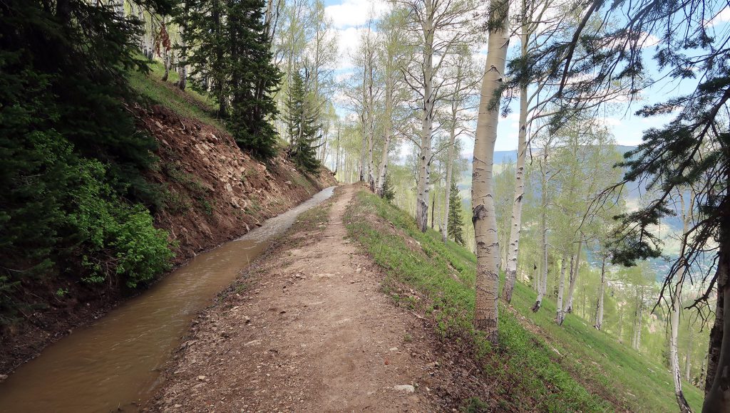 A drainage ditch flows with spring snowmelt alongside Scottie's Trail.